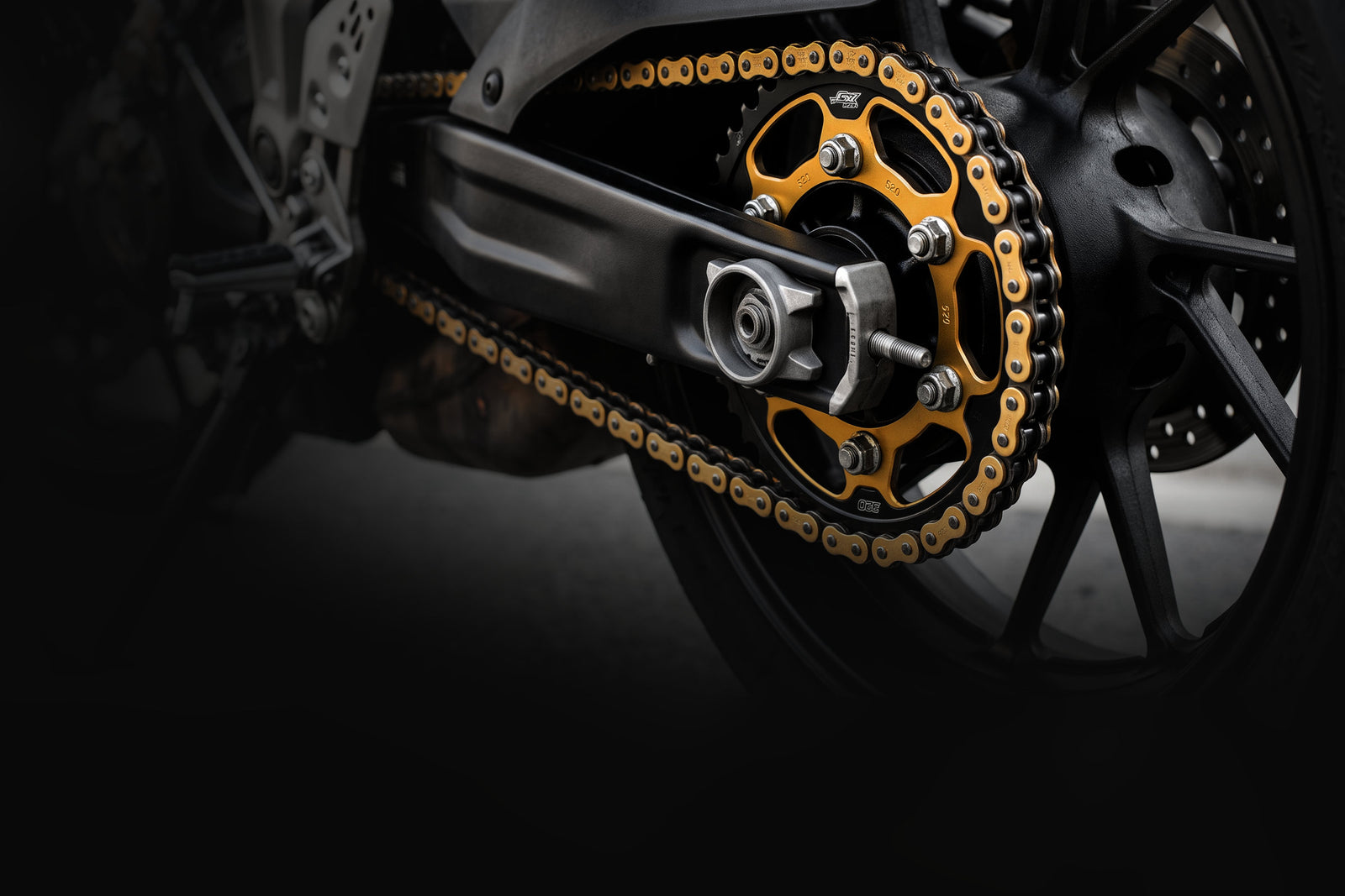 Gold chain and rear sprocket on a sportbike swingarm