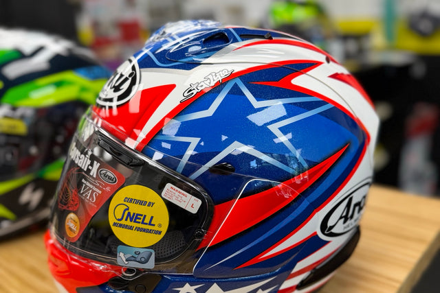 Arai Corsair-X full-face helmet with a Snell certification sticker on the visor, on the counter at Indy Superbikes